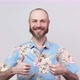 Happy bearded man wearing hawaiian shirt showing thumbs up over white background. - VideoHive Item for Sale