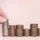A woman's hand puts coins in a column. Investment concept. Metallic currency. - VideoHive Item for Sale
