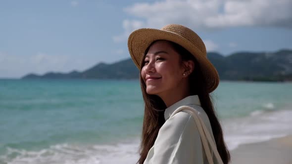 Slow motion of a beautiful young asian woman with hat on the beach