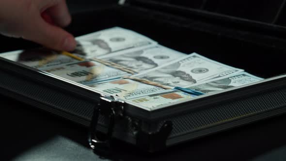 Counting American Hundred Dollar Banknotes Putting Money in Metallic Suitcase