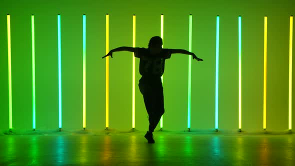 Sportive Girl Street Dancer Performing Hip Hop Movement in the Studio Against the Backdrop of Neon
