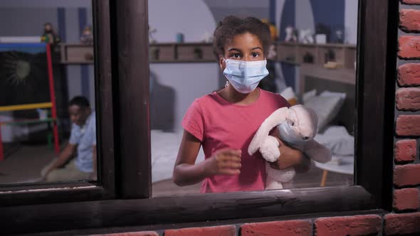 Dark-skinned Schoolgirl in Medical Mask By Window