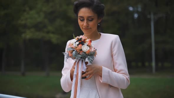 Stylish Bride with a Beautiful Bouquet of Flowers in the Park