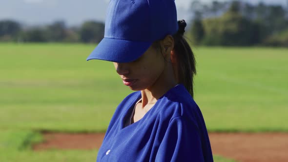 Portrait of happy mixed race female baseball player, on field smiling