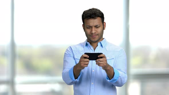 Young Enthusiastic Indian Man Playing Video Games on His Smartphone