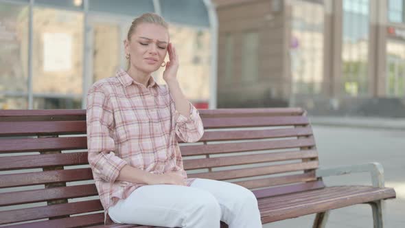 Young Woman with Headache Sitting Outdoor on Bench