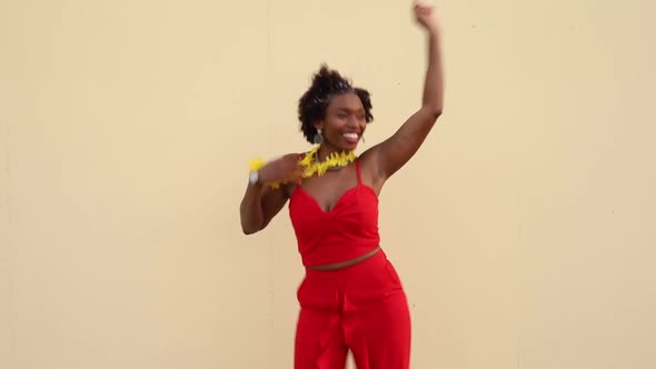 Happy African American woman dancing near white wall
