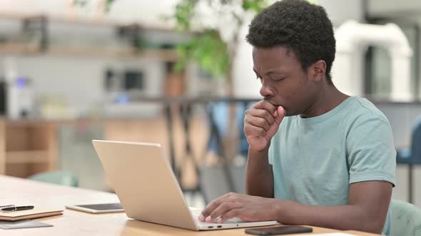 Sick Young African Man with Laptop Coughing