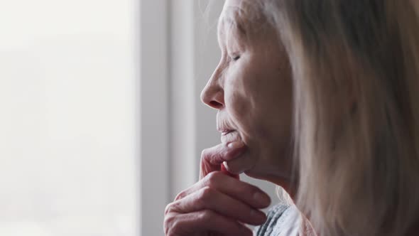 Sad Lonely 70 Years Old Senior Woman Looking Through the Window