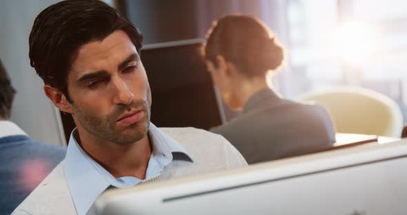 Male business executive working on computer with coworkers