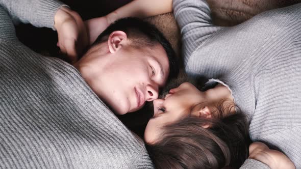 Couple in Silver Sweaters Lying on Floor and Kissing at Home