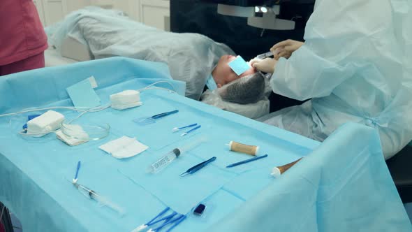 Surgeon is Performing Eye Operation Near a Desk with Medical Tools