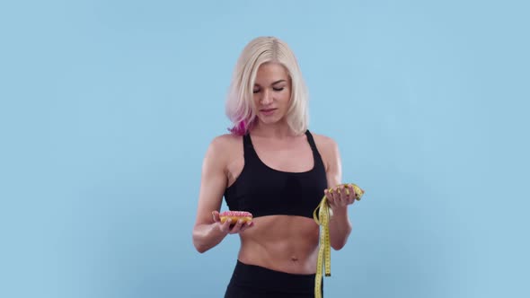 Sporty Woman with Press in Sports Uniform Holds Donut and Measuring Tape in Her Hands She Raises