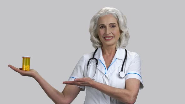 Happy Old Doctor Showing Can of Pills with Her Palms Up