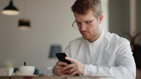 Adult Man is Viewing Social Media and Reading News in Mobile Phone Using Free Internet in Cafe