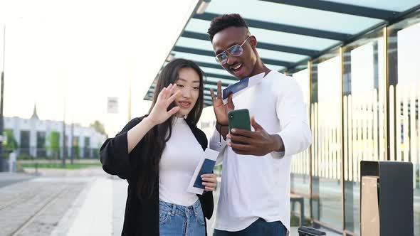 Mixed Race People Standing on Modern tram Station and Have Video Call on Smartphone