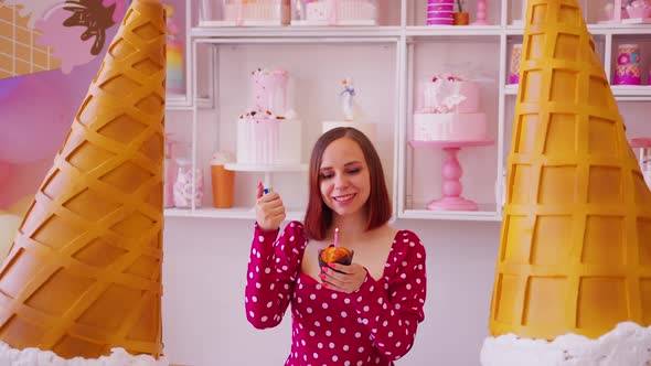 Young Woman in Red Dress Lighting Candle in Muffin