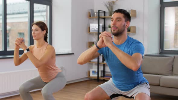 Happy Couple Exercising and Doing Squats at Home