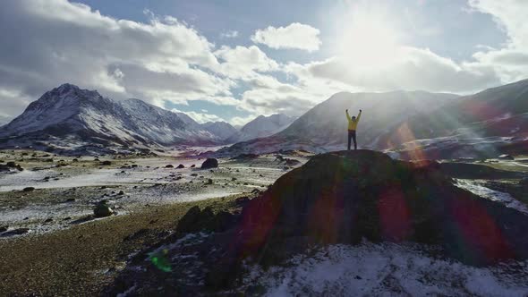 Male Mountain Climber Raising Hands with Icepick on Top of Snowy Peak