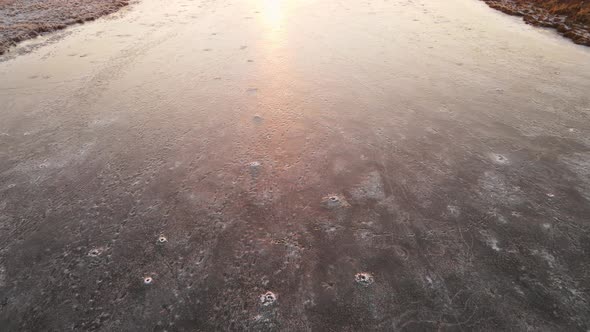 Icy Surface of the Lake with the Reflection of the Orange Light of the Sun