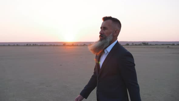 Handsome Bearded Mature Man in Suit Walking Outdoors on Beach During Sunset Slow Motion