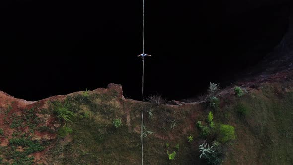 Top View on a Huge Natural Pit and a Man Slacklining Over It
