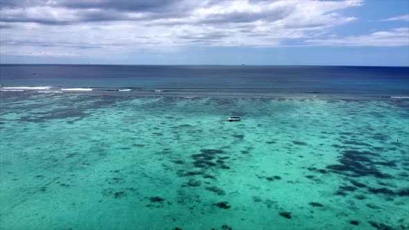 Slow aerial dolly shot of boat riding across crystal clear indian ocean