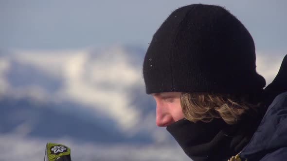 Portrait of a young man snowboarder on a scenic snow covered mountain top