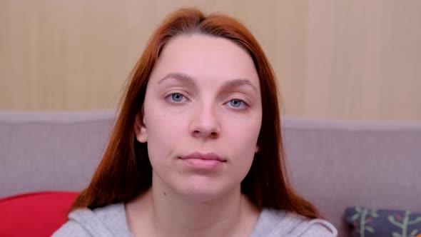 Woman Is Sitting on the Couch and Looking at the Camera.