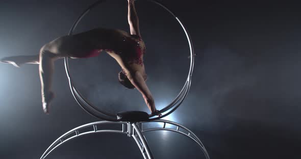 Fit Young Woman in Red Costume is Spinning in a Hoop and Doing Gymnastics