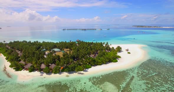 Aerial drone view of a scenic tropical island resort hotel in the Maldives.
