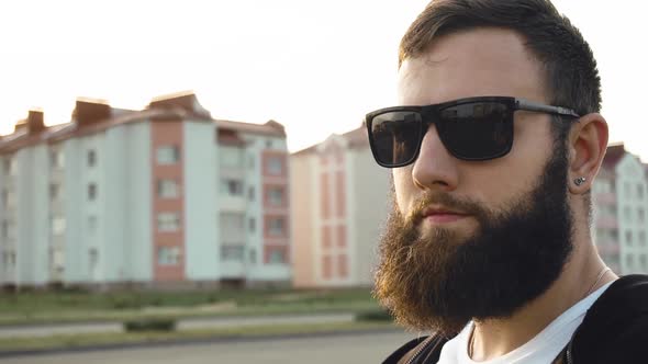 Portrait of Bearded Brutal Image Guy in Black Glasses. Fashionable Stylish Man Is at Sunset in City