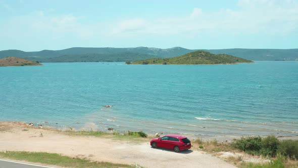 Auto on Steep Beach Against Hilly Green Islands in Azure Sea