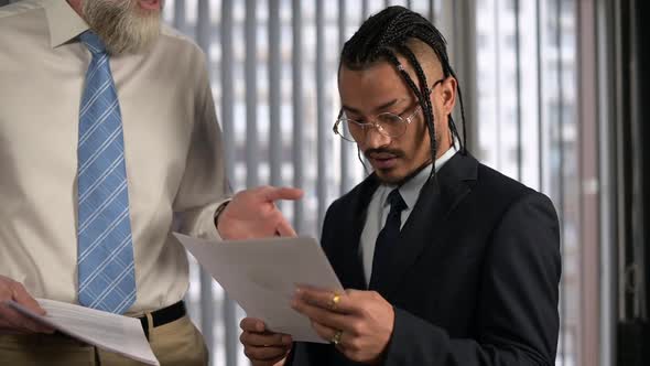 A young office worker listens to the conversation of colleagues in the office.