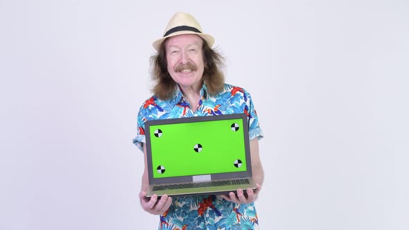 Happy Senior Tourist Man Thinking While Showing Laptop