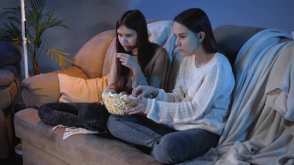 Friends Eating Popcorn From Big Bowl While Watching TV Show in Living Room at Night