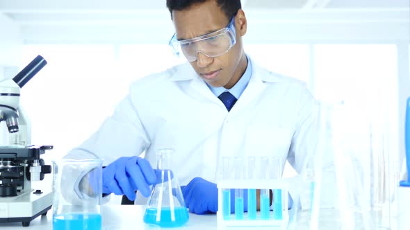 Research Scientist Looking at Blue Solution in Flask in Laboratory