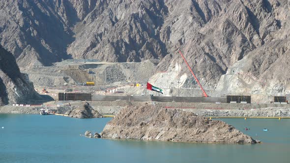 UAE Flag waving by construction site and kayaks in the Hatta Dam Lake