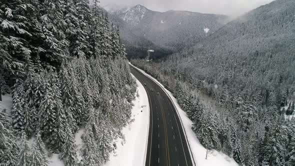Snow Falling Aerial Over Mountain Valley Forest Road