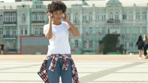 Woman Putting on Headphones and Dancing Outdoors, Freedom From Prejudice