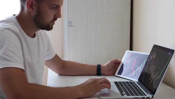 Man Looking at Finance Chart on Laptop and Tablet Day Trader Investing From Home