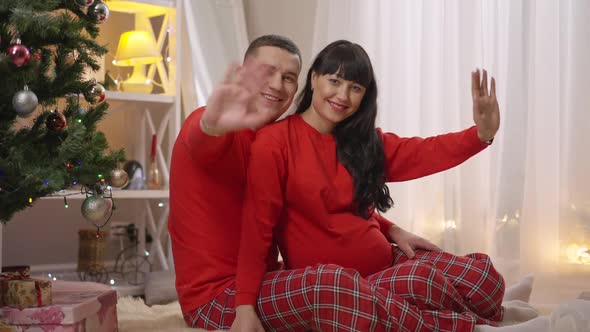 Happy Smiling Pregnant Woman and Man in Similar Red Pajamas Looking at Camera Waving in Slow Motion