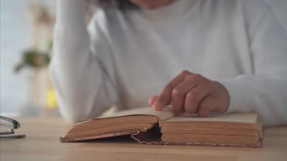 African American Woman with an Afro Hairstyle Reading a Book at the Table Close Up