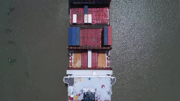 Top down aerial view of the stern and bridge of a large container ship on a sunny day. Visible is ra