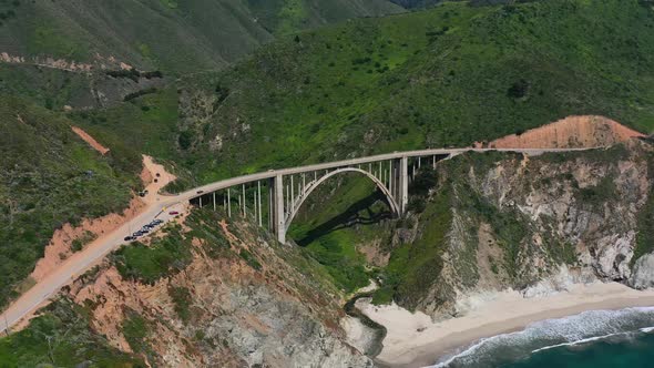 Wide aerial view of Bixby Creek Bridge on a sunny summer day in Big Sur California with the white sa