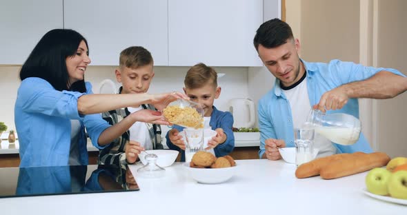 Happy Family which Sitting Together Around the Table in the Kitchen and Has Breakfast 