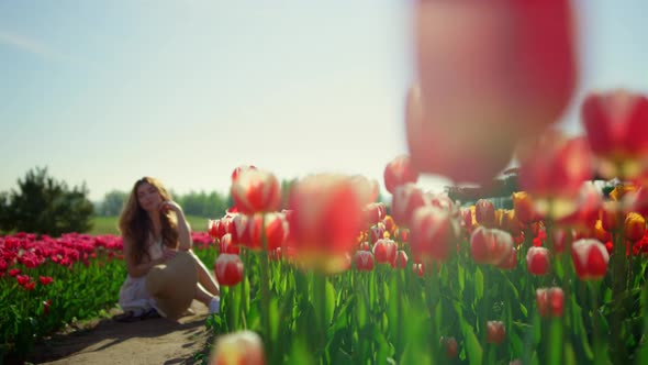 Spring Flower Garden in Bloom with Unrecognizable Girl Sitting on Road