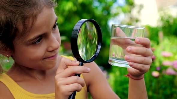 The Child Examines the Water Through a Magnifying Glass