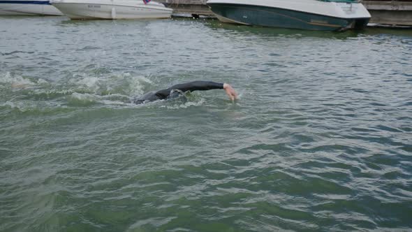 Pro Swimmer in a Wetsuit Swims in Open Water an Athlete Trains Before a Triathlon Competition