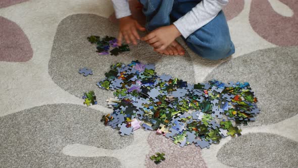 A Preschool Girl Sits on a Carpet and Collects Colorful Puzzles